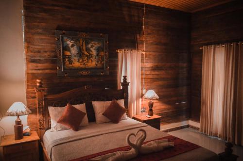 a bedroom with a bed with wooden walls and two lamps at The Valley Green Cottage in Nusa Penida