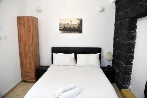 a bedroom with a bed with white sheets at Domos Tiberias דומוס טבריה in Tiberias
