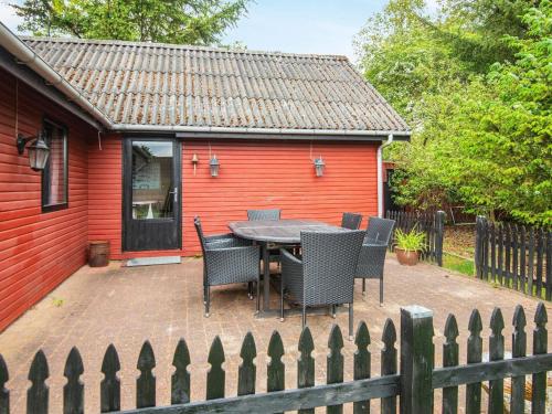 eine Terrasse mit einem Tisch und Stühlen vor einem roten Haus in der Unterkunft 6 person holiday home in Vemb in Vemb