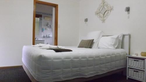 a bedroom with a large bed with white sheets at Karuah Motor Inn in Karuah
