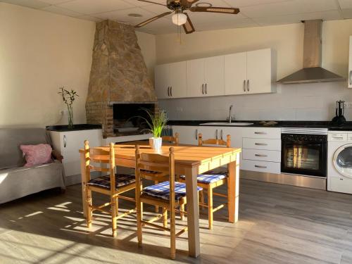 a kitchen with a wooden table with chairs and a stove at Cal Music in El Poblenou del Delta