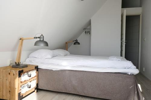 a bedroom with a bed and a nightstand with a lamp at Vingården i Arild in Arild