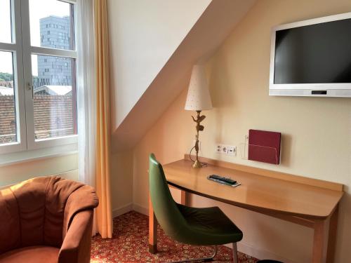 a room with a desk and a chair and a television at GAIA Hotel Basel - the sustainable 4 star hotel in Basel
