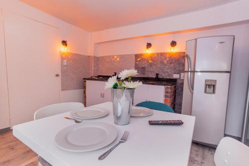 a kitchen with a table with plates and a refrigerator at ApartaSuites & Hotel Bogota Suamox in Bogotá