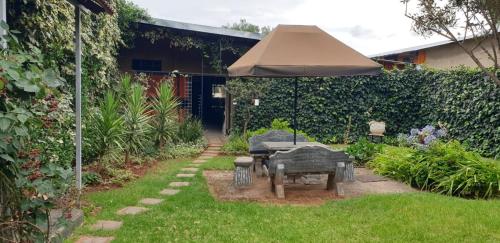 un jardín con mesa y sombrilla en VESA Guesthouse, en Meyerton
