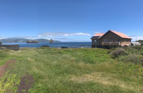 a house on a hill next to the ocean at Casa-do-Mar in Madalena