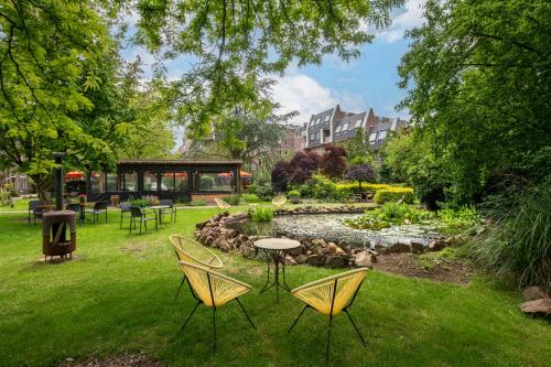 een tuin met stoelen en een tafel en een vijver bij Kloosterhotel de Soete Moeder in Den Bosch