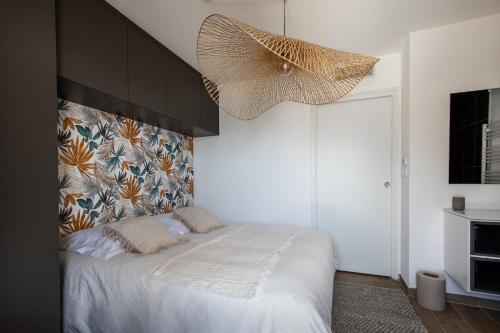sypialnia z łóżkiem i dużym żyrandolem w obiekcie Superbe appartement bord de mer w mieście Saint-Mandrier-sur-Mer