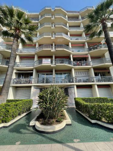 un grand bâtiment avec des palmiers devant dans l'établissement Grand Sud Promenade Suite, à Nice