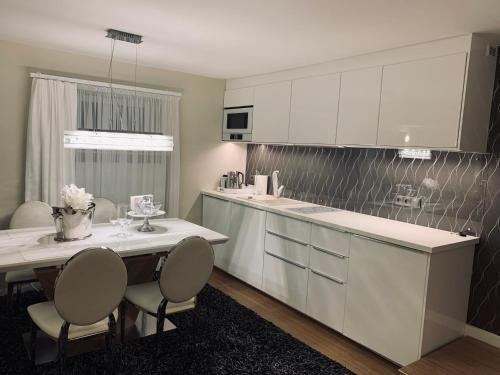a kitchen with white cabinets and a table and chairs at Apartament z prywatnym, krytym basenem in Sopot