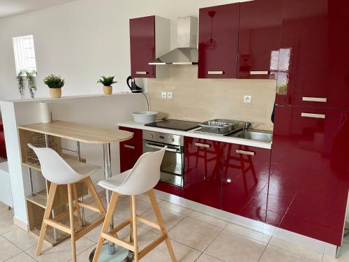 une cuisine avec des armoires rouges et une table et des chaises dans l'établissement CHAP'S Résidence en centre ville 1 à 11 personnes, à Sully-sur-Loire