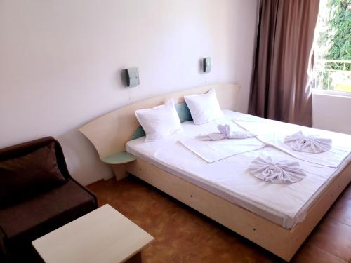 a bedroom with a white bed with a chair and a window at Family Hotel Magnolia, Sunny Beach in Sunny Beach