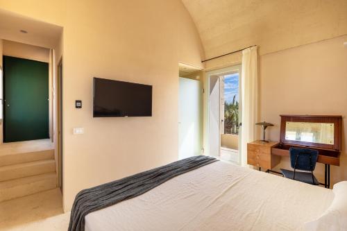 a bedroom with a bed and a desk and a television at Il Giardino Grande - Dimora in Salento in Parabita