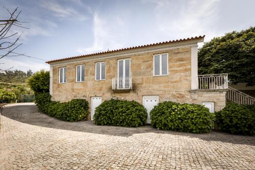 a brick house with bushes in front of it at Casa de Ferreira Cinfães in Cinfães
