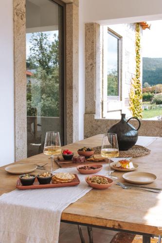a table with glasses of wine and food on it at Quintal Country Houses in Vila Praia de Âncora