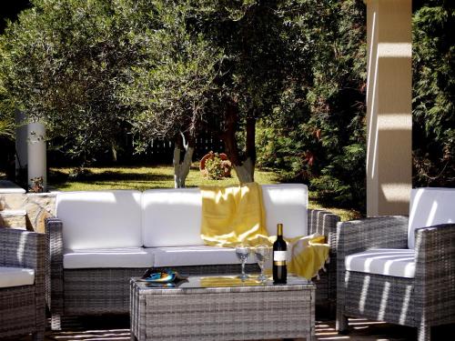 a white couch on a patio with a bottle of wine at Villa Afroditi, Spartia, Kefalonia in Kefallonia