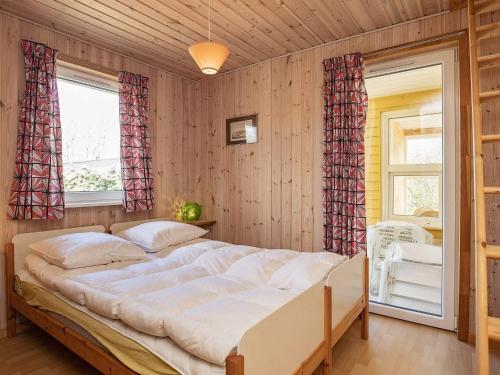 um quarto com uma cama grande e 2 janelas em Holiday home Thyholm XVI em Thyholm