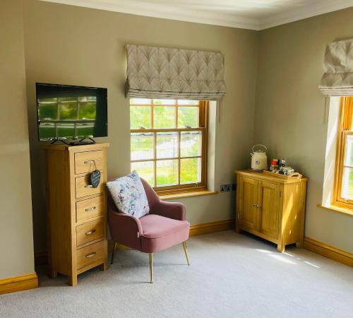 Habitación con silla, cómoda y ventanas en Riverside House en York