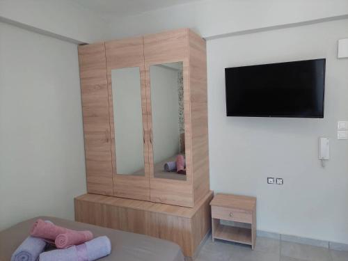 een slaapkamer met een grote houten kast en een flatscreen-tv bij Old Town Harmony Apt in Kos-stad