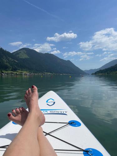 a woman with her feet on a paddle board on a lake at Ferienwohnungen im Haus Sonnleiten am Weissensee in Techendorf