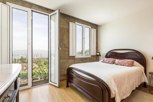 a bedroom with a bed and large windows at Casa de Ferreira Cinfães in Cinfães