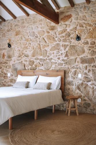 a bedroom with a stone wall with a bed at Quintal Country Houses in Vila Praia de Âncora
