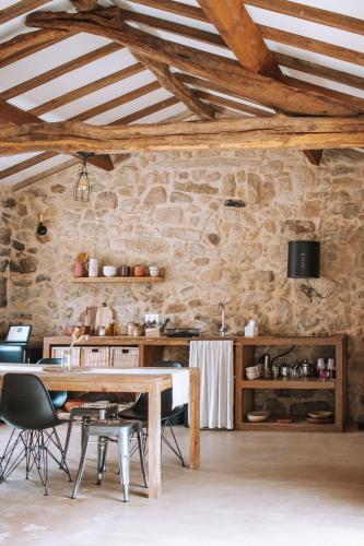 a dining room with a table and a stone wall at Quintal Country Houses in Vila Praia de Âncora