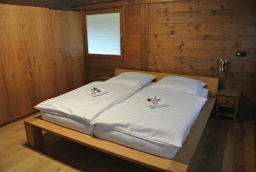 a bed in a wooden room with two white pillows at Komfort Chalet in Itter