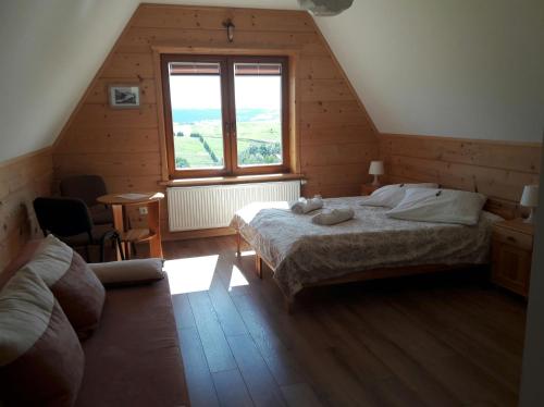 a attic bedroom with a bed and a window at Willa Grywałd in Grywałd