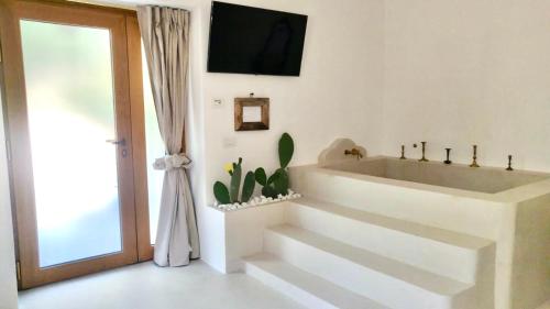 Baño blanco con escaleras y TV en la pared en MAREULIVI, en Ostuni