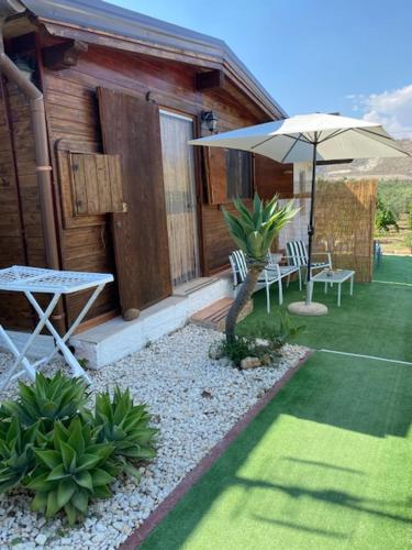 a patio with an umbrella and a table and chairs at La Bianca Scogliera in Realmonte