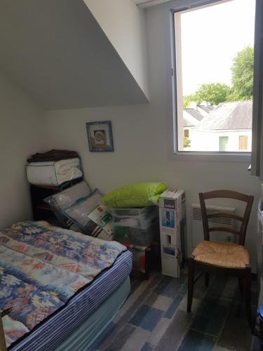 a bedroom with a bed and a chair and a window at Chez Christine in Ploemel