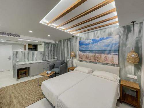 a bedroom with a large white bed and a kitchen at Gran Marina Suites in Las Palmas de Gran Canaria