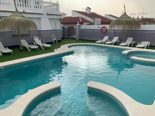 a large swimming pool with chairs and a building at Apartamentos Costa Luz in Matalascañas