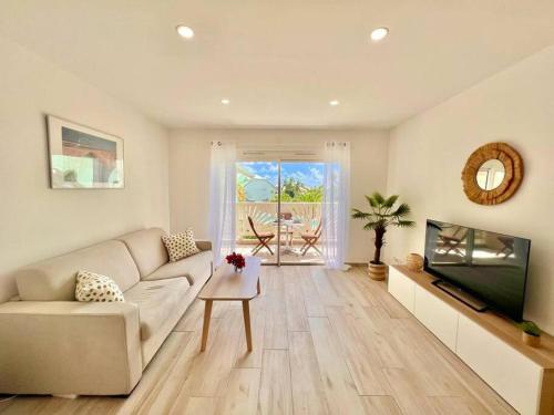 a living room with a couch and a flat screen tv at Maracuja 17, Orient Bay village, walkable beach at 100m in Orient Bay