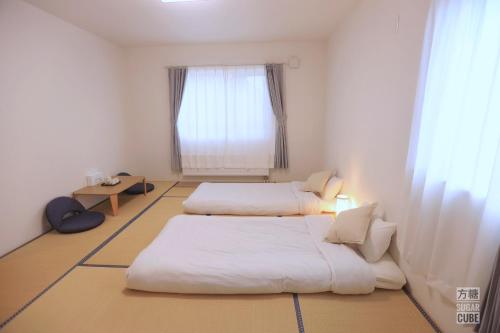 two beds in a small room with a window at Furano CUBE SUGAR-方糖民宿,步行8min到雪场,3 brs,Max 6ppl in Furano