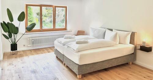 1 dormitorio con 1 cama con sábanas blancas y ventana en Bungalow in Rottachs Bestlage en Rottach-Egern