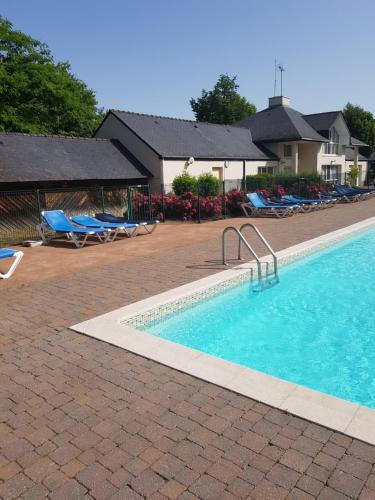 une piscine avec des chaises longues et un complexe hôtelier dans l'établissement Chez Christine, à Ploemel