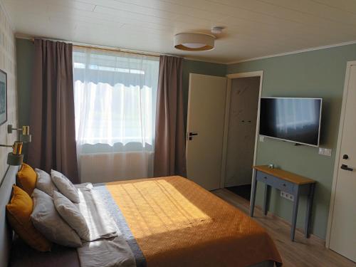 a bedroom with a bed and a flat screen tv at Liisu Külalistemaja in Haapsalu