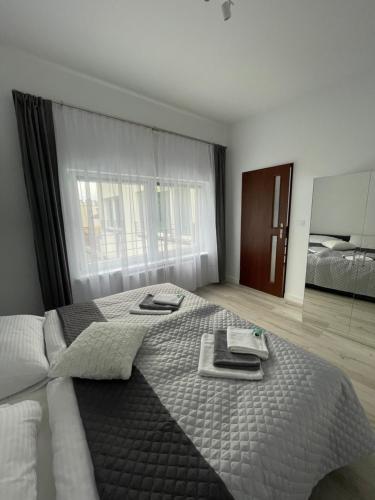 a bedroom with a large bed with towels and a mirror at Apartamenty "SZKIEŁKO" in Koszalin