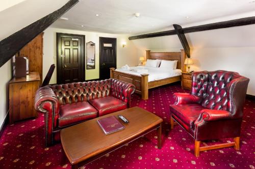 a hotel room with a bed and leather furniture at Bagdale Hall in Whitby