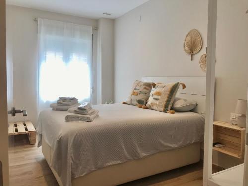 Dormitorio blanco con cama y ventana en Apartamento equipado playa Valencia OnesDeMar en Valencia