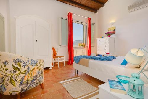 a bedroom with a bed and a chair and a window at Villa Rosa Dei Venti - Scopello-Villas in Scopello