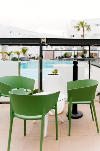 two green chairs and a table on a balcony at Aequora Lanzarote Suites in Puerto del Carmen