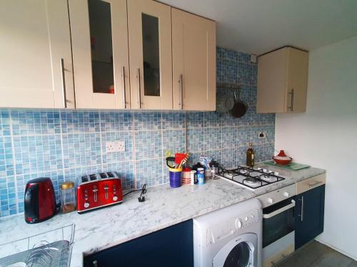 a kitchen with a stove and a washing machine at Owl Haven: Comfortable central 3 bedroom house, with an enclosed garden. in Bicester