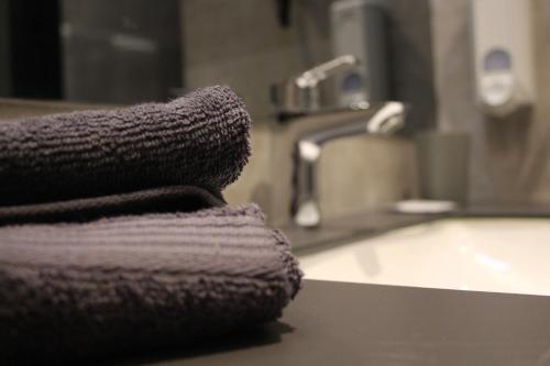- une pile de serviettes assises au-dessus d'un lavabo dans la salle de bains dans l'établissement Hotel-VH, 