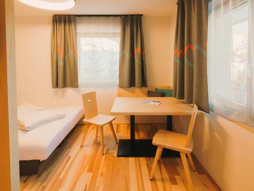 a room with a bed and a desk and a table at Alpin - Studios & Suites in Warth am Arlberg