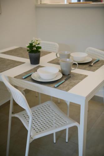 une table blanche avec des assiettes et des tasses dessus dans l'établissement Chamonix 27 - Au Centre Vue Mont Blanc et Jardin, à Chamonix-Mont-Blanc