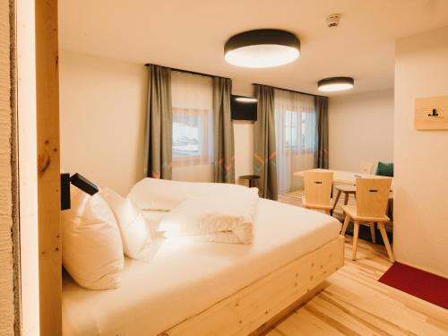 a bedroom with a bed with white pillows at Alpin - Studios & Suites in Warth am Arlberg