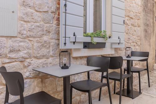 two tables and chairs in front of a stone wall at Heritage Rooms Split Olympic Dream in Split